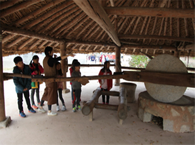 연자방아에 대한 설명을 듣고있는 어린이들